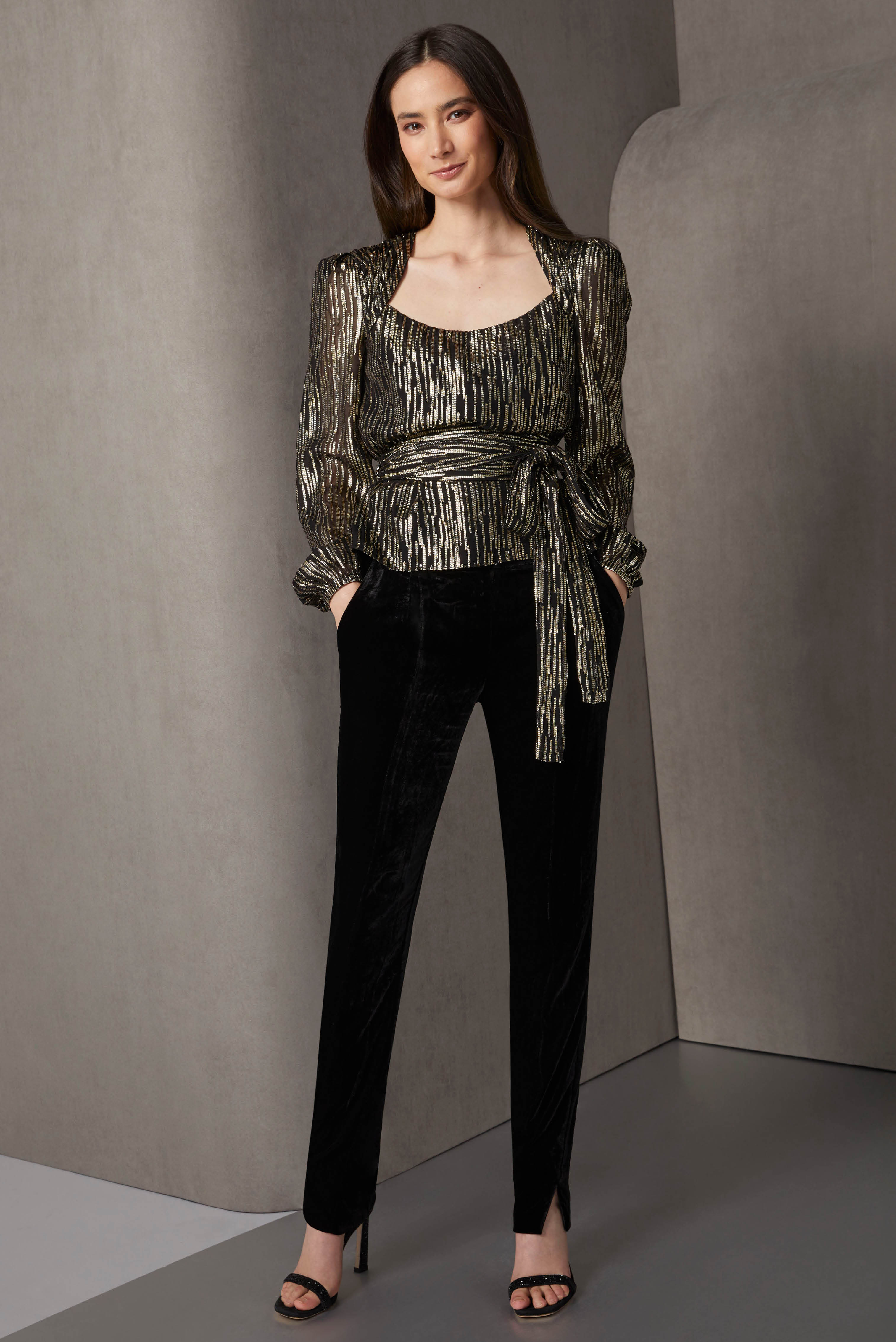 This elegant pants ensemble adroitly combines glamour with wearability. The sparkling fil coupé evening blouse with gold stripe motifs has a portrait neck, gathered shoulders, and elasticized puff sleeves.