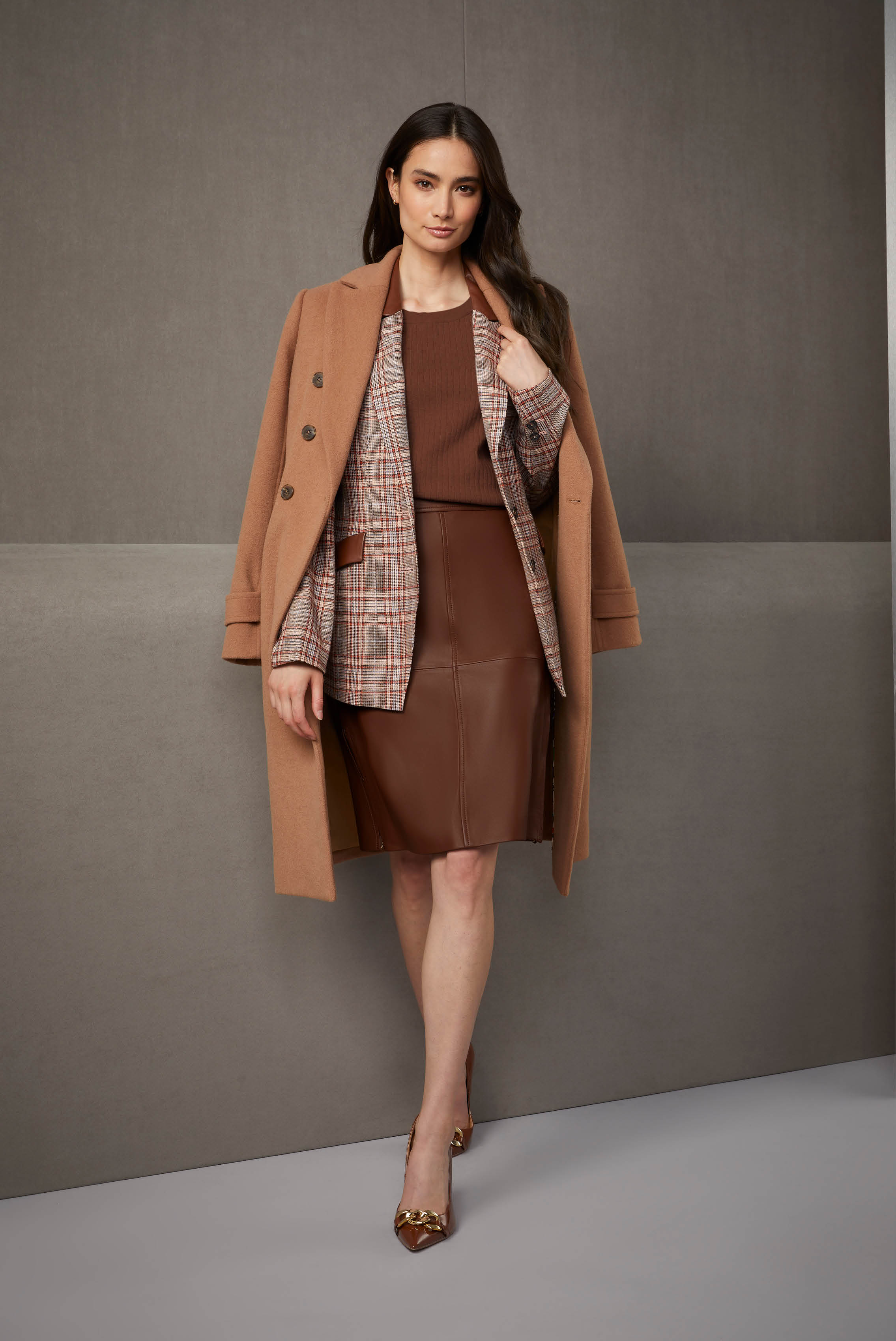 The combination of a deep caramel ribbed cotton knit top, luxe leather skirt, and Italian plaid riding jacket creates a sophisticated ensemble that exudes timeless charisma.