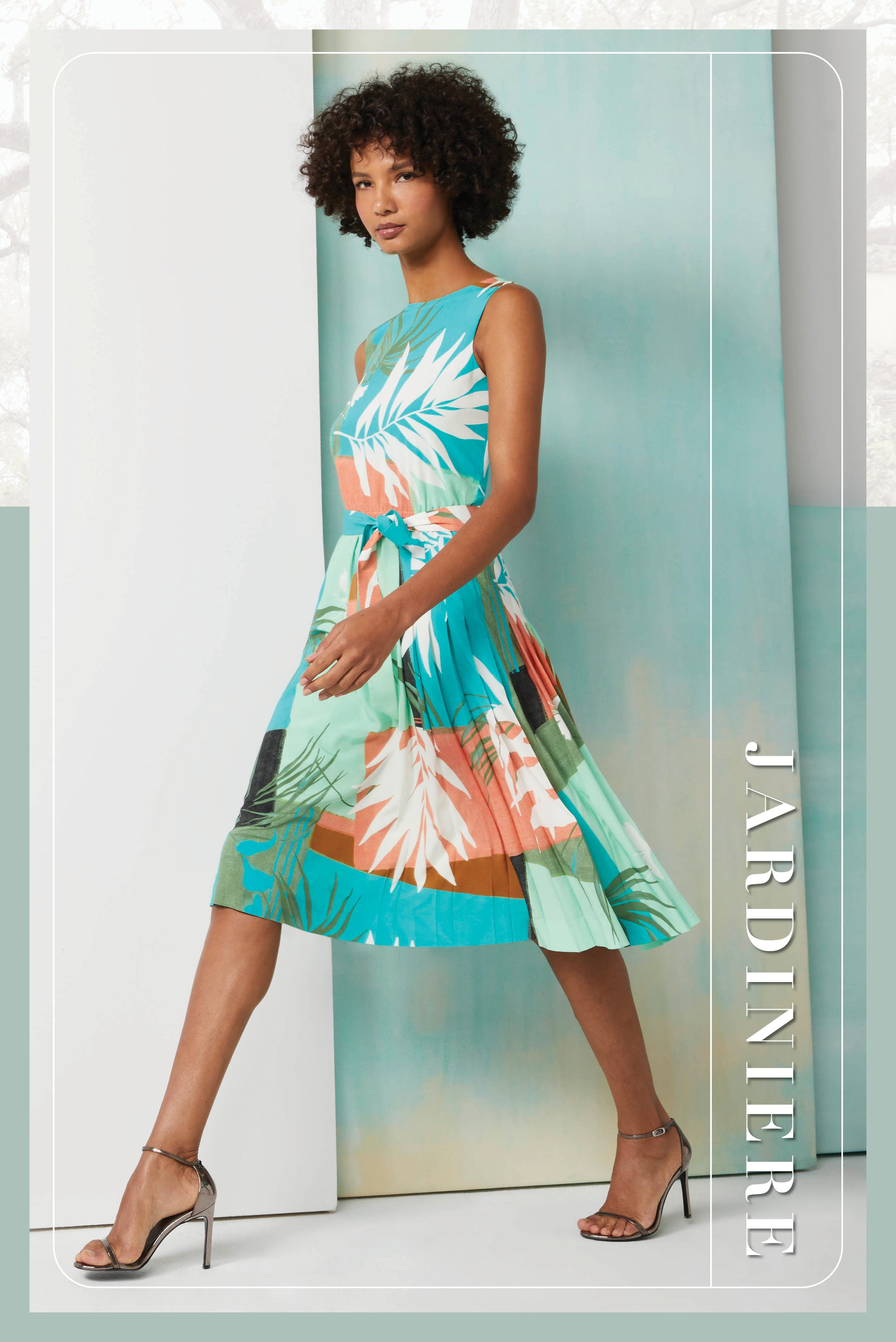 Photo of a model wearing the Jardiniere dress, which is a tropical-print, stretch silk pleated dress.