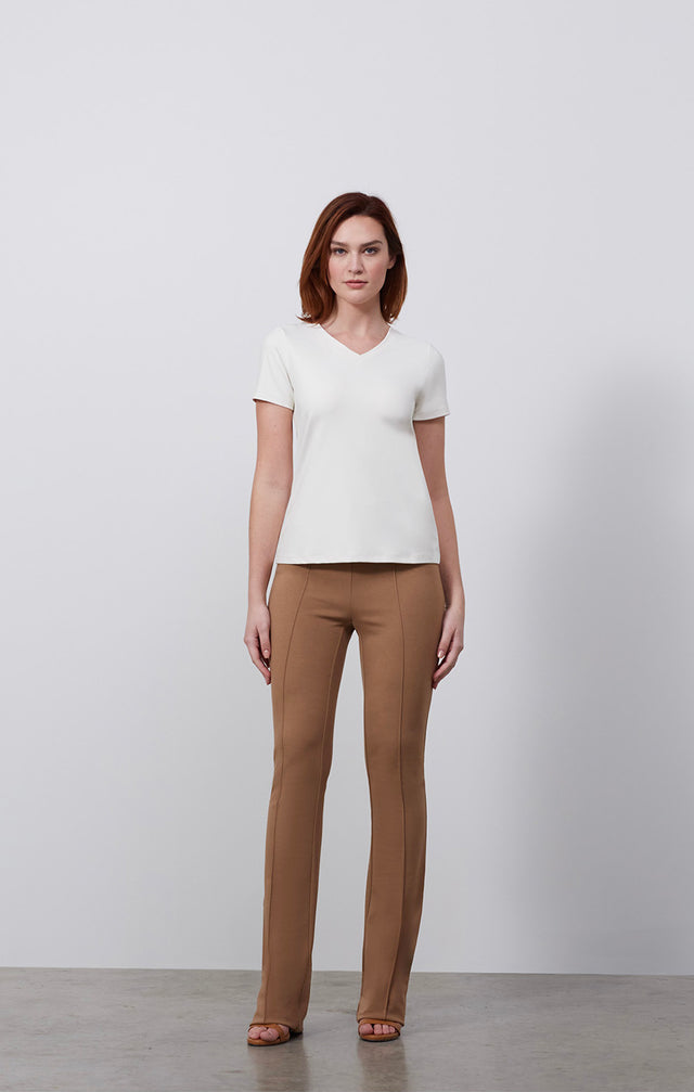 Ecomm photo of a model wearing the Paradigm-Ivr shirt, which is a fitted ivory v-neck tee shirt.