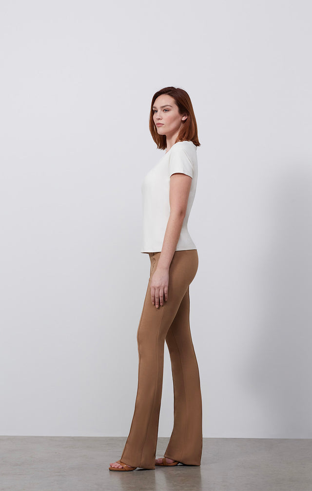 Ecomm photo of a model wearing the Paradigm-Ivr shirt, which is a fitted ivory v-neck tee shirt.