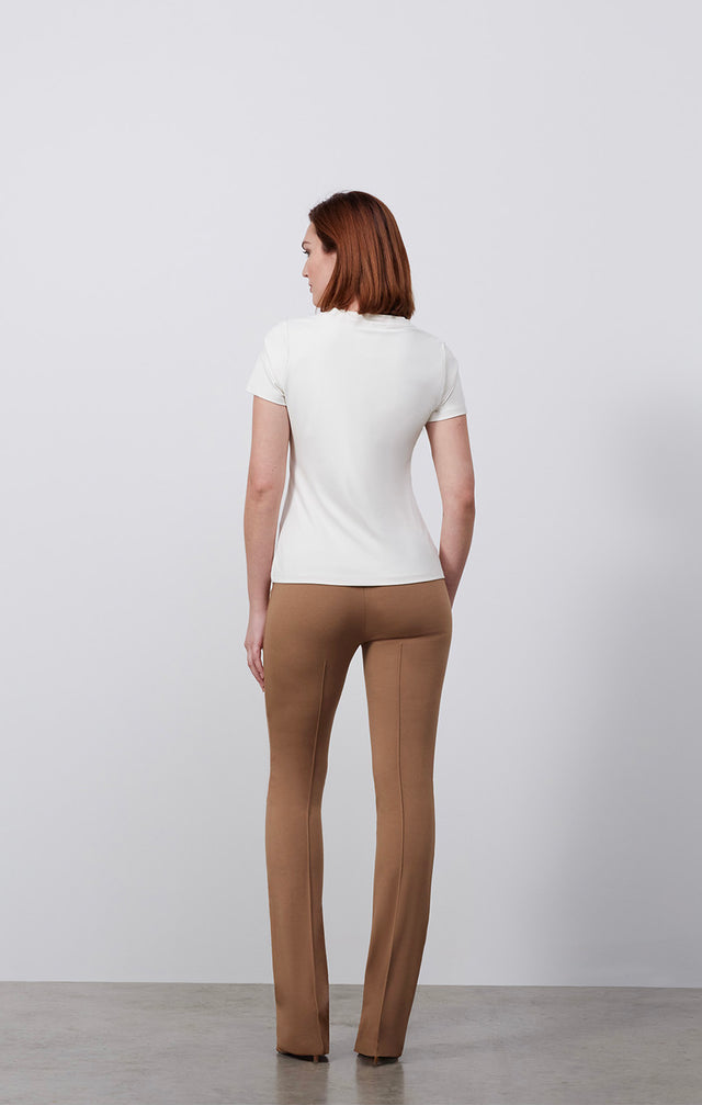 Ecomm photo of a model wearing the Paradigm-Ivr shirt, which is a fitted ivory v-neck tee shirt.